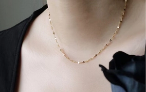 Dettaglio di una catena minimalista in oro indossata da una modella per un look chic
