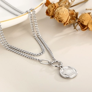 Detail of silver double-layer necklace featuring crown and queen engraved round pendant