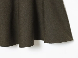Detailed close-up of dark olive fabric texture with precision hem stitching and drape