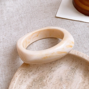 Detailed close-up of marble pattern resin wide bangle on elegant stone tray display
