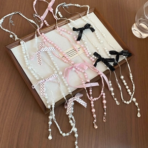 Detail of bowknot pearl necklaces with crystal pendants on a wooden jewelry display tray