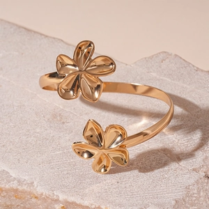 Détail d'un bracelet jonc doré fleuri avec deux fleurs à cinq pétales sur pierre brute