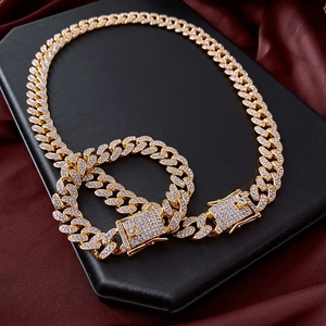 Close-up of iced-out gold Cuban link necklace and bracelet set on red silk backdrop