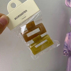 Set of two rectangular hair clips in amber and lime green colors in packaging