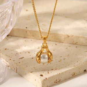 Detailed close-up of golden heart pendant with pearl on a textured limestone surface