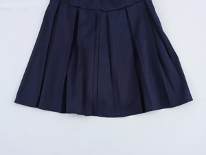 Dettaglio dell'orlo a pieghe blu scuro e del tessuto pregiato di questo abito stile collegio