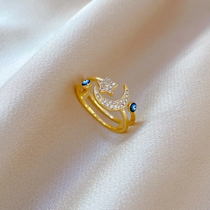 Macro shot of gold-plated star and moon ring with evil eye enamel on champagne silk