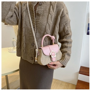 Détail du sac en paille tressée avec rabat en cuir rose et boucle fleurie blanche