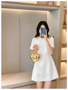 Golden heart-shaped evening bag with chain strap held by a model in a white dress