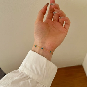 Detailed view of a gold Mobius bracelet featuring a blue stone on a woman's wrist