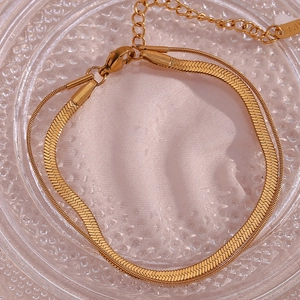 Macro detail of gold double-layer snake chain bracelet with 18K tag and lobster clasp