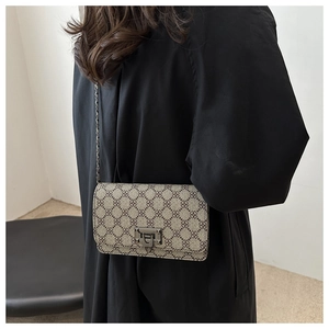 Close-up of vintage monogram crossbody bag with chain strap on a model shoulder