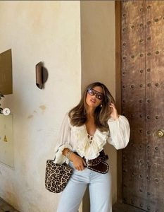 Chiffon V-neck blouse with ruffle trim paired with jeans and a leopard print bucket bag
