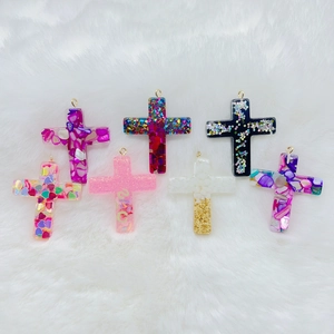 Handmade resin cross pendants in seven colors with gold loops on white faux fur