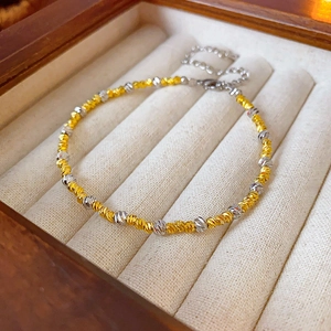 Close-up of 18k gold and silver two-tone beaded bracelet in a beige suede jewelry box