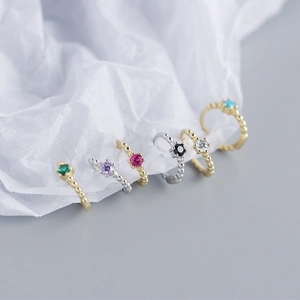 Close-up of S925 sterling silver hoop earrings with diverse colorful gemstones on white paper