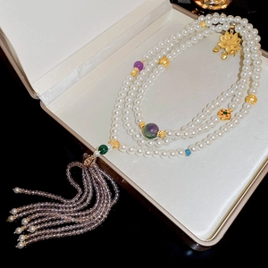 Detail of multi-layer pearl necklace with golden lotus pendant and beaded tassels