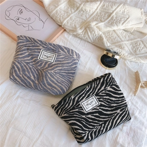 Close-up of zebra pattern chenille fabric cosmetic bag with Time to Party woven label
