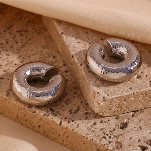 Detailed macro view of silver hammered metal earrings on natural stone and silk texture
