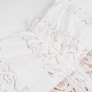 Close-up of elegant white floral lace texture and stitching on a strapless trailing dress