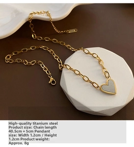 Close-up of gold titanium heart necklace with NEVER FORGET engraving on stone display