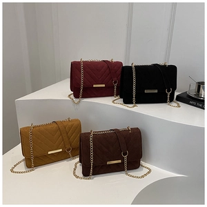 Detail of V-quilted chain bags in burgundy, black, yellow, and brown suede finish