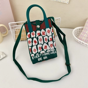 Close-up of green knit crossbody bag with Mahjong motifs and metal buckle closure