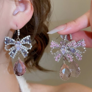 Detail of silver bow earrings with sparkling purple and pink zircon crystal drops