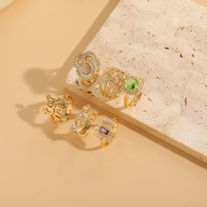 Detailed close-up of 14K gold plated geometric rings with zircon insets on stone props