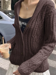 Street style shot of a dark brown button-up knit cardigan with a classic cable pattern
