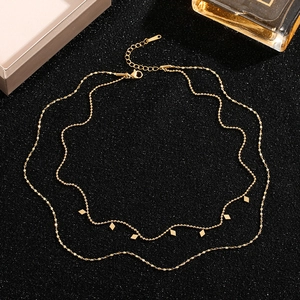 Double-layered gold titanium steel necklace with rhombus charms on black textured background