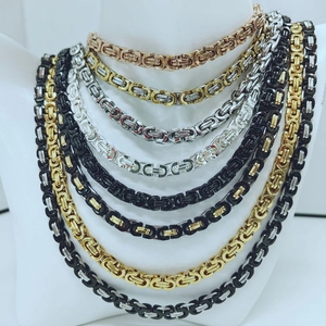 Close-up of layered stainless steel chains in gold, silver, and black on a mannequin