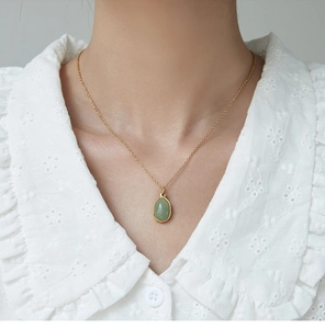 Close-up of a green aventurine drop pendant on an 18K gold-plated titanium necklace