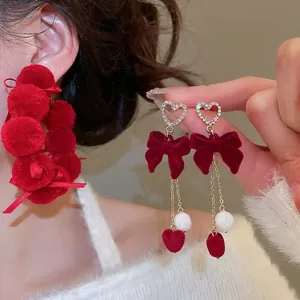 Elegant red velvet bow earrings with diamond-encrusted heart studs and soft pompom drops