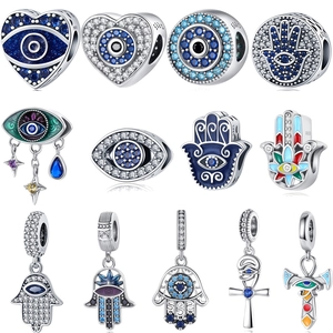 Macro view of S925 sterling silver evil eye and Hamsa hand charms with crystal inlays