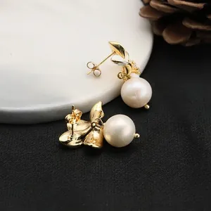 Elegant gold leaf earrings with white pearls and small zircons on marble background
