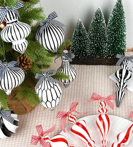 Close-up of black, white, and red patterned glass Christmas ornaments with plaid ribbons