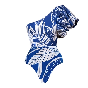 Detail of blue one-shoulder swimsuit with white tropical leaf print and ruffled sleeve