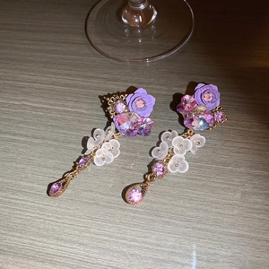 Close-up of purple crystal flower earrings with resin petals on gray wood texture