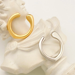 Ear cuff irregolari in oro e argento presentati su una scultura a busto classica