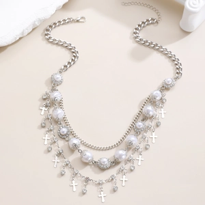 Dettaglio di collana argento multistrato con perle e croci su sfondo minimalista