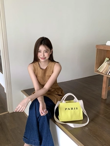 Lifestyle view of a yellow woven tote bag with Paris print and long shoulder strap