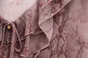 Detailed close-up of snake print blouse neckline with ruffled edges and gold buckle