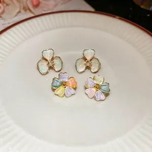 Exquisite 18k gold plated acrylic flower stud earrings with pearls in a white ceramic dish