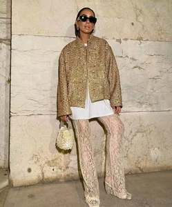 Dettaglio giacca in tweed dorato con paillettes da donna, pantaloni in pizzo e borsa di perle