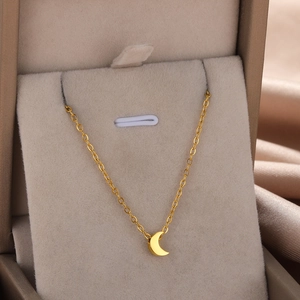 Detailed view of a gold moon pendant necklace resting in a beige velvet jewelry box