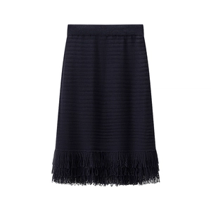 Detailed view of the dark blue knit skirt featuring dense fringe tassels on the hemline