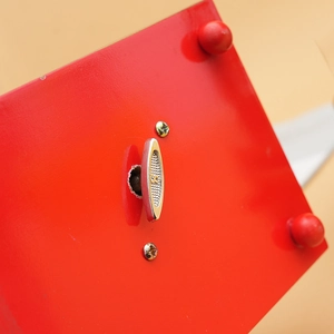 Macro view of mechanical wind-up key and polished red wooden base of a music box
