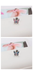 Détail de boucles d'oreilles papillon avec zircons roses et bleus sur cuir blanc pur