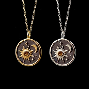 Detailed close-up of gold and silver sun moon coin necklaces with amber center stones